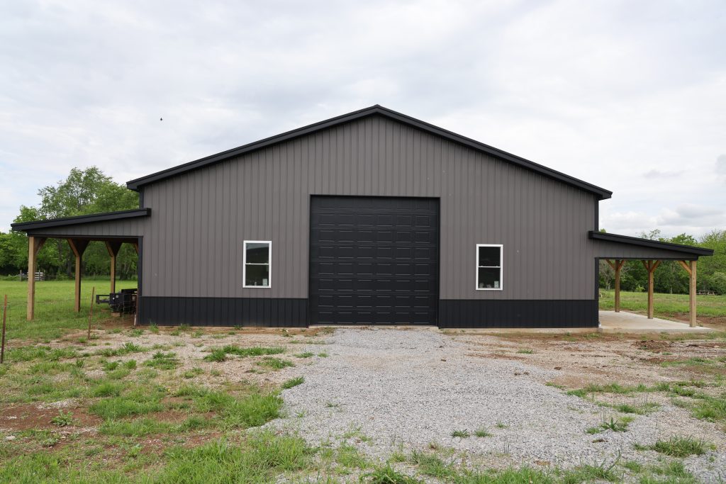 Two-colored metal shop with large garage door, windows, and a lean-to.